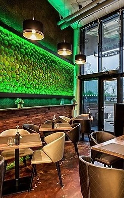 reštaurácia so zelenou stenou a drevenými stolmi a stoličkami a bar s televízorom na stene machovy obraz, stabilizovany mach, machová stena, machová dekorácia